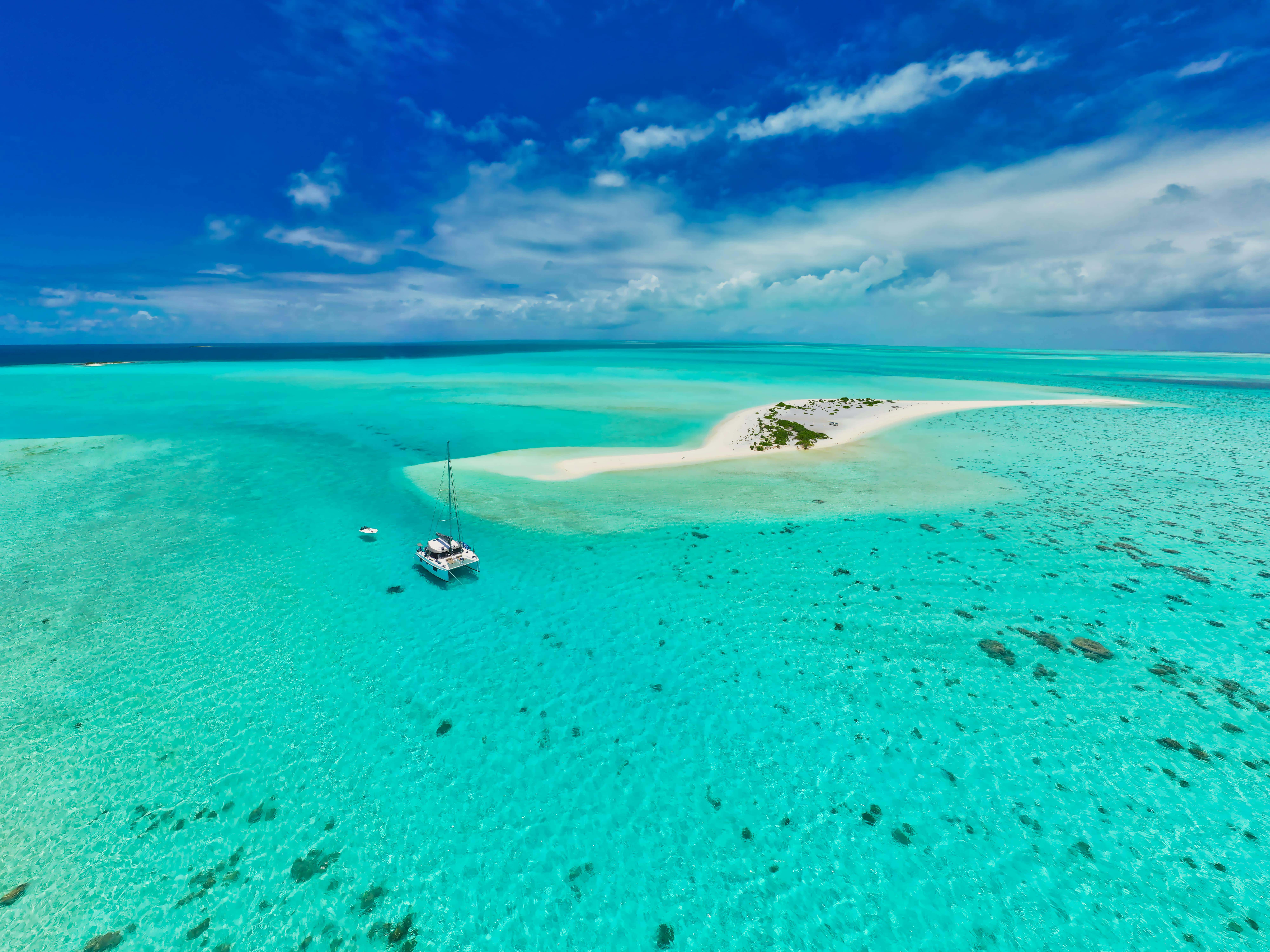Stunning tropical island with turquoise waters and a sailboat under a blue sky.
